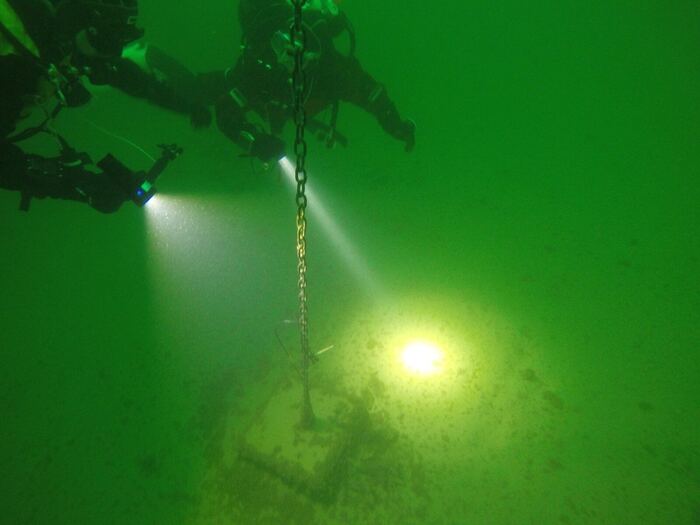 Mooring on the lake floor: concrete block with chain, inspected by a diver with headlamp (GoPro shot).