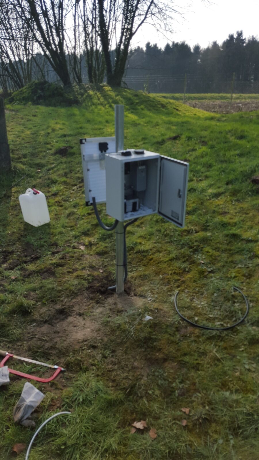 Geöffneter Pegel-Schaltschrank im Grünland, frisch installierte Messstation
