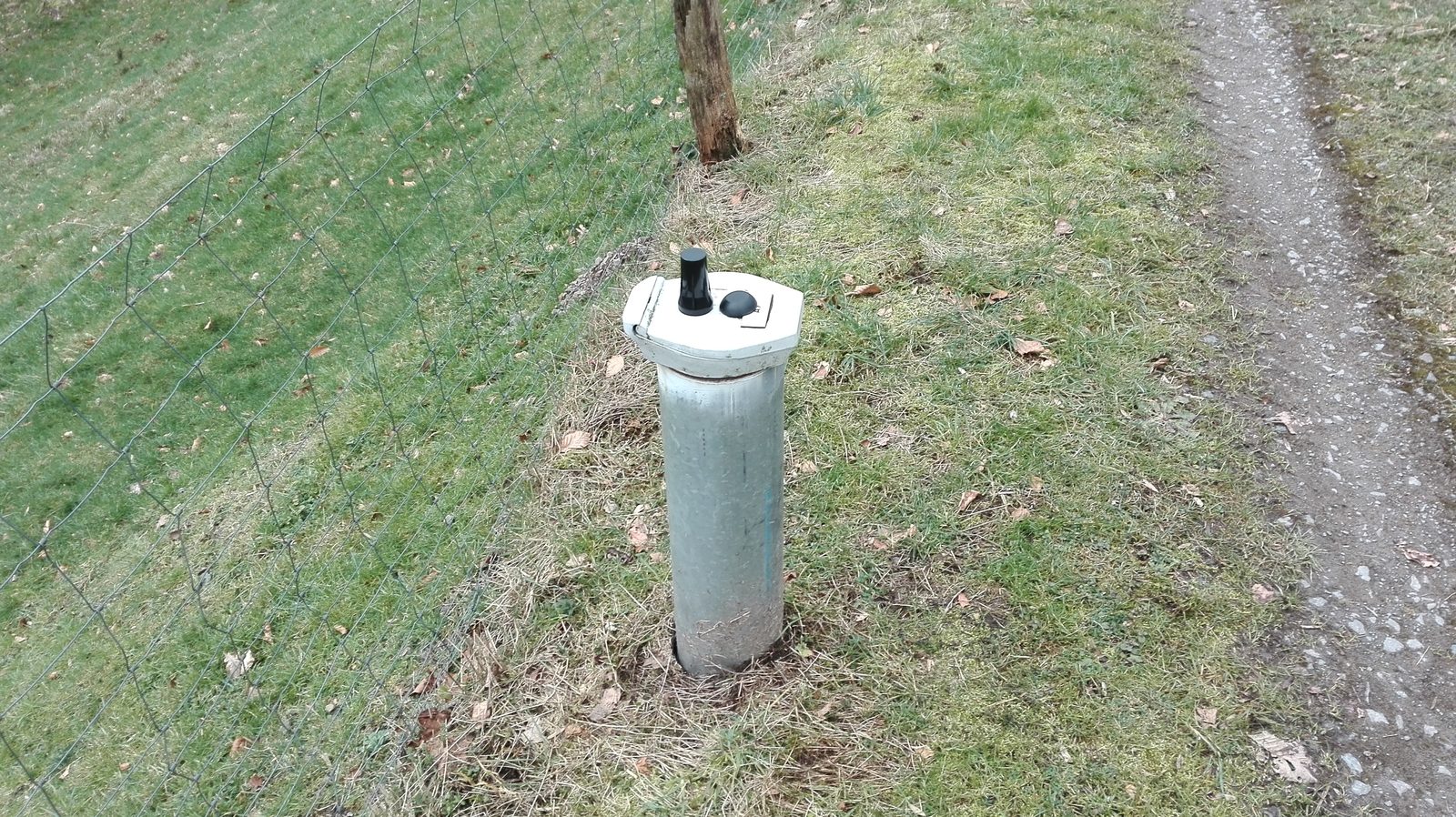 Klassischer Grundwasser-Pegel im Acker mit Schutzaufsatz und Pegelpfeife