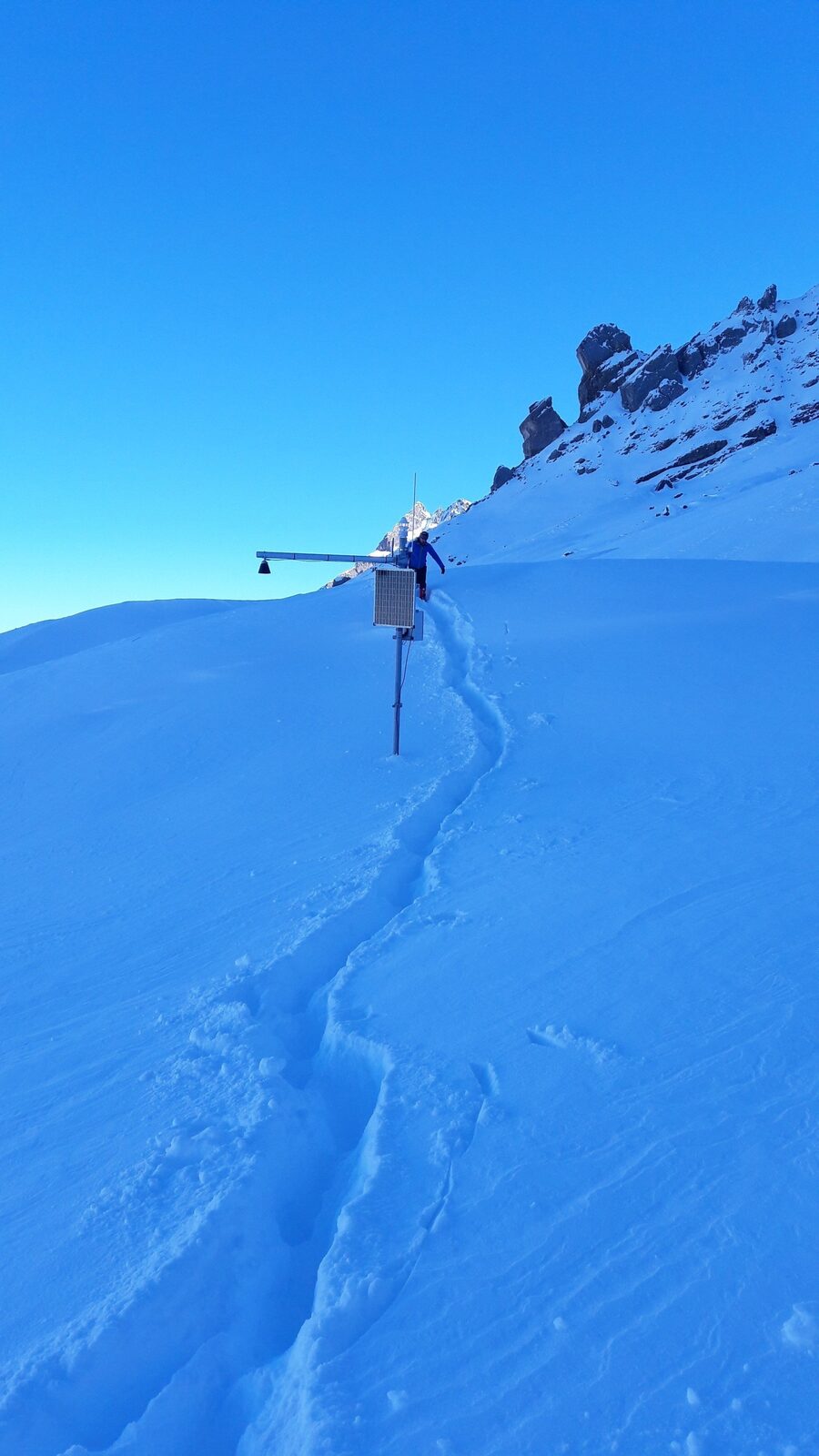Klimastation in den Alpen: Solarmodul und Datenlogger im Schnee, Wartungseinsatz im Spätwinter.