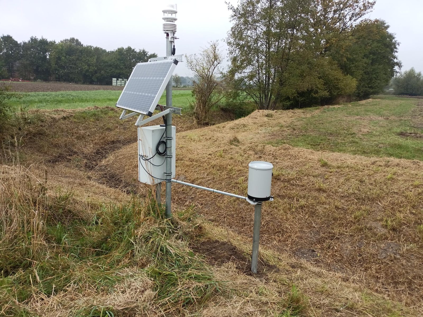 Klimastation mit Niederschlagssensor und Solarpanel am Feldrand bei Herbstwetter